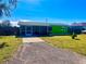 Single-story home showcasing vibrant green paint, a screened-in porch, and a long driveway at 30431 Holly Rd, Punta Gorda, FL 33982