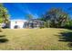 Large backyard with screened enclosure, lush lawn, and mature trees at 18565 Edgewater Dr, Port Charlotte, FL 33948