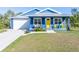 Charming blue house with a yellow door, white garage, and landscaped lawn at 28492 Royal Palm Dr, Punta Gorda, FL 33982