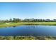 Pond and green golf course in the background with lush trees and clear blue skies at 12470 Wellen Golf St # 203, Venice, FL 34293