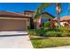 Exterior view of a tan house with a two car garage and landscaped yard at 2427 Daisy Dr, North Port, FL 34289