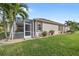 Back exterior view showing house with screened patio and lawn at 25554 Prada Dr, Punta Gorda, FL 33955