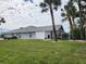 Charming single-story home featuring a lush green lawn and mature palm trees in a desirable neighborhood at 23176 Lindale Ave, Port Charlotte, FL 33954