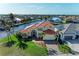 Canal-front home with tile roof, lush landscaping, and brick driveway at 1245 Whippoorwill Ct, Punta Gorda, FL 33950