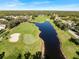 Aerial view of a golf course community with houses, a pond, and lush green landscape at 13761 Long Lake Ln, Port Charlotte, FL 33953