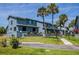 Coastal townhome showcasing blue exterior, manicured lawn, palm trees, and walkway on a sunny day at 1839 Settlers Dr # B-6, Nokomis, FL 34275