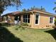 Back exterior view of a tan house with a large window and grassy yard at 4530 Turnberry Cir, North Port, FL 34288