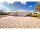 Rear house view showing a three-car garage and paver driveway at 13204 Kakapo Ave, Port Charlotte, FL 33981