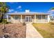 Front view of a yellow house with a metal roof, porch, and landscaping at 13204 Kakapo Ave, Port Charlotte, FL 33981