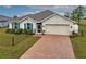 One-story home with light beige walls, blue shutters, and a brick paver driveway at 16039 Quinta Dr, Punta Gorda, FL 33955