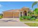 Tan two-story house with a three-car garage and lush landscaping at 1906 Creek Nine Dr, North Port, FL 34291