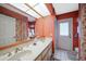 Bathroom boasts dual sinks, coral walls, and an exterior access door at 21241 Winside Ave, Port Charlotte, FL 33952