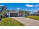 Single-story home with a modern facade, dark garage door, and a landscaped lawn at 2418 Frantz St, North Port, FL 34286