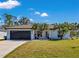 White house with black garage door, palm trees, and a well-manicured lawn at 2418 Frantz St, North Port, FL 34286