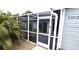 White-framed screened patio entrance with gray siding and landscaping at 3300 Loveland Blvd # 3303, Punta Gorda, FL 33980