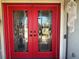 Red double front doors with glass inserts and decorative accents at 3761 Peace River Dr, Punta Gorda, FL 33983