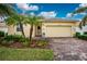 Bright yellow house with palm trees, brick driveway and well-manicured landscaping at 6139 Grand Cypress Blvd, North Port, FL 34287
