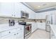 White kitchen features stainless steel appliances and a tile backsplash at 6139 Grand Cypress Blvd, North Port, FL 34287