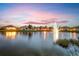 Scenic lakefront view of homes at sunset with a water fountain at 6139 Grand Cypress Blvd, North Port, FL 34287