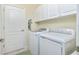 Bright laundry room with white cabinets, washer, and dryer at 6139 Grand Cypress Blvd, North Port, FL 34287