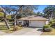 Single-story home with a two-car garage and mature oak tree at 10810 Cedar Breaks Dr, Port Richey, FL 34668