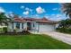 Single-story home with red tile roof, attached garage, and landscaped yard at 3191 Village Ln, Port Charlotte, FL 33953