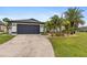 Beautiful home with a landscaped lawn, palm trees, and a dark-colored garage door at 7424 S Moss Rose, Punta Gorda, FL 33955