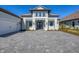 Two-story home with a gray tile roof, white walls, and a paver driveway at 10628 Nicklaus Ct, Englewood, FL 34223