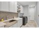 Laundry room featuring a farmhouse sink, stylish tile, and ample storage at 10628 Nicklaus Ct, Englewood, FL 34223