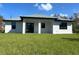 Rear view of house showcasing a covered patio and grassy backyard at 12547 Trinity Ave, Port Charlotte, FL 33953