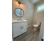 Modern bathroom with white vanity, round mirror, and gray floor at 16305 Branco Dr, Punta Gorda, FL 33955