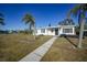 Front view of a white house with palm trees and walkway at 230 Waterway Ne Cir, Port Charlotte, FL 33952