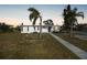 Front view of a white house with palm trees and walkway at dusk at 230 Waterway Ne Cir, Port Charlotte, FL 33952