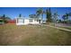 Front view of a white house with palm trees and walkway at 230 Waterway Ne Cir, Port Charlotte, FL 33952