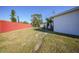 Side yard with red fence and grassy area at 230 Waterway Ne Cir, Port Charlotte, FL 33952