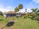 Spacious backyard with pool and screened enclosure. Lush landscaping and palm trees at 2408 Silver Palm Rd, North Port, FL 34288