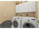 Laundry room with washer, dryer, and overhead cabinets at 24424 Buckingham Way, Punta Gorda, FL 33980