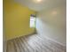 Bedroom with laminate flooring, a window, and a bright yellow accent wall at 4269 River Bank Way, Port Charlotte, FL 33980