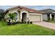 Tan house with tile roof, two-car garage, and manicured lawn at 4269 River Bank Way, Port Charlotte, FL 33980