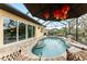 Screened-in pool with tiled steps, patio and umbrella with decorative lanterns at 8242 Lakeside Dr, Englewood, FL 34224