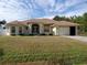 One-story home with a tan exterior, lush lawn, and a two-car garage at 1057 Staley St, Port Charlotte, FL 33952