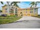 Two-story building with yellow exterior, palm trees, and driveway at 115 Breakers Ct # 111, Punta Gorda, FL 33950
