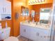 Clean bathroom with a double vanity, bright orange walls, and a walk-in shower at 2180 Heron Lake Dr # 108, Punta Gorda, FL 33983