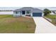 One-story home with gray siding, attached garage, and landscaped yard at 27 Meadowlark Ln, Placida, FL 33946