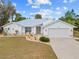 White single-story house with gray door, two-car garage, and landscaping at 28434 Sabal Palm Dr, Punta Gorda, FL 33982