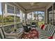 Relaxing screened lanai with wicker furniture, ceiling fan, and view of lush landscaping at 3112 Club Dr # 124, Port Charlotte, FL 33953