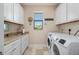 Bright laundry room with washer, dryer, and ample cabinetry at 1406 Mediterranean Dr, Punta Gorda, FL 33950