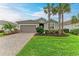 Single-story home with a paved driveway, lush lawn, and palm trees at 15169 Spanish Point Dr, Port Charlotte, FL 33981