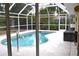 Inviting screened-in pool with clear water and a relaxing patio area surrounded by lush greenery at 21217 Knollwood Ave, Port Charlotte, FL 33952