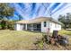 Back of house featuring a screened porch and grassy yard at 437 Loveland Blvd, Port Charlotte, FL 33954